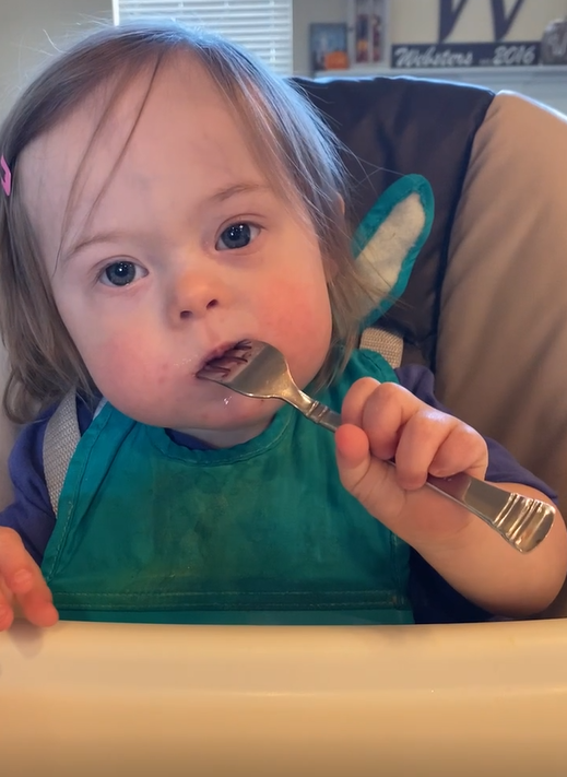 Toddler with Down syndrome feeds with fork
